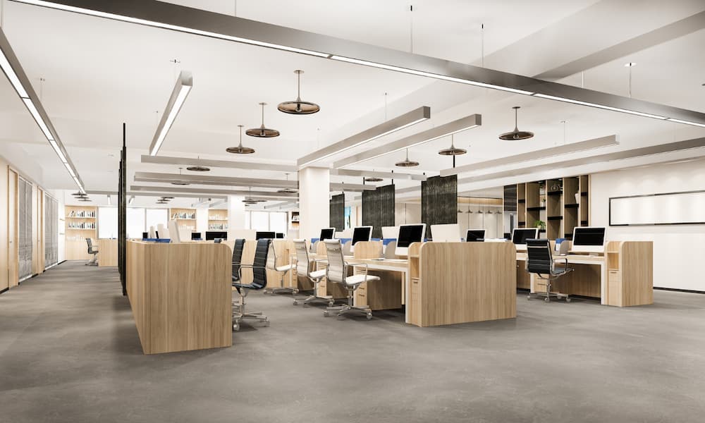 Modern open-plan office with wooden desks, ergonomic chairs, and ceiling lighting in a spacious workspace
