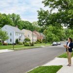 A real estate agent standing on a sidewalk in a suburban Connecticut neighborhood