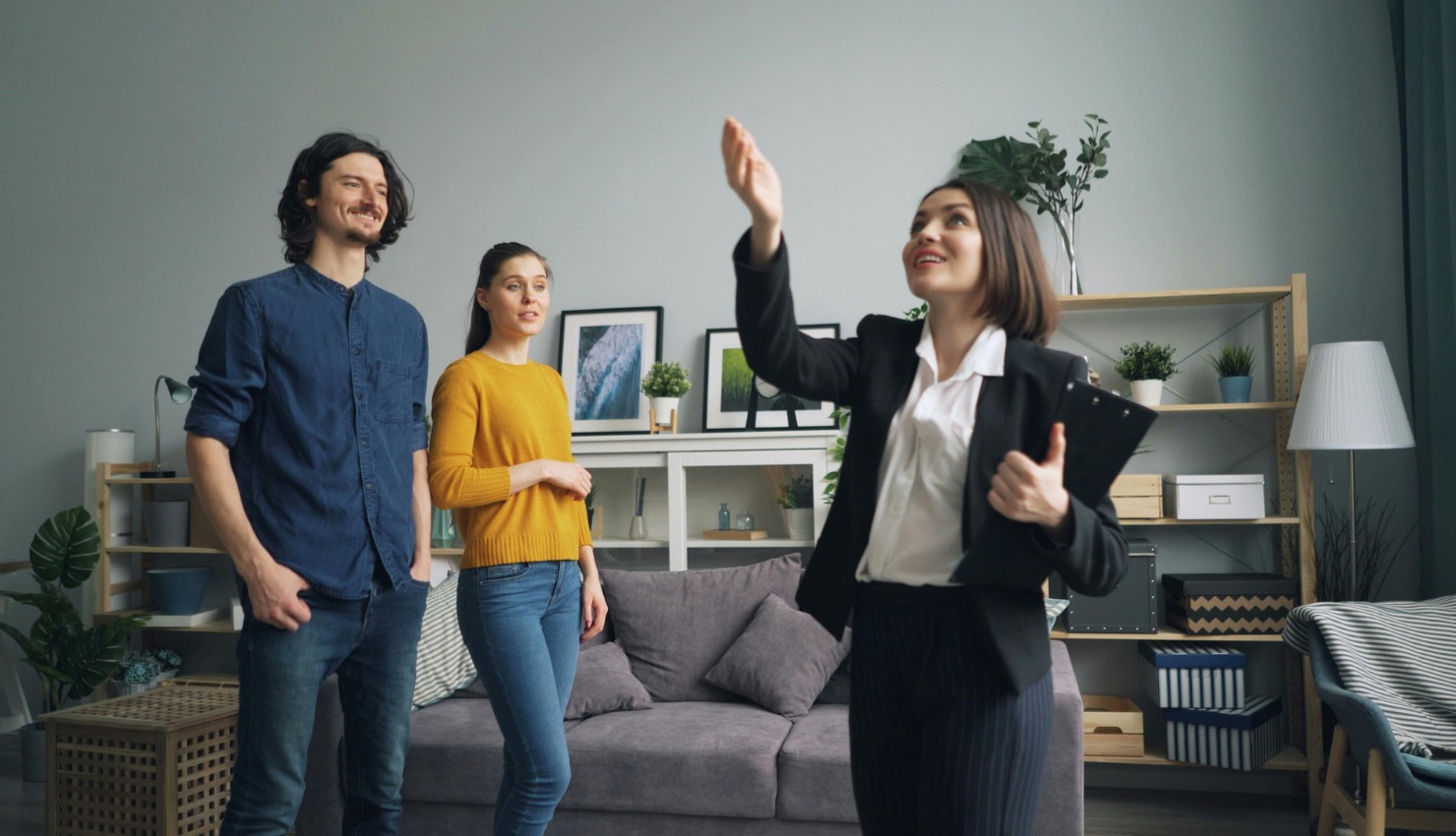 a female residential real estate agent gestures toward the ceiling