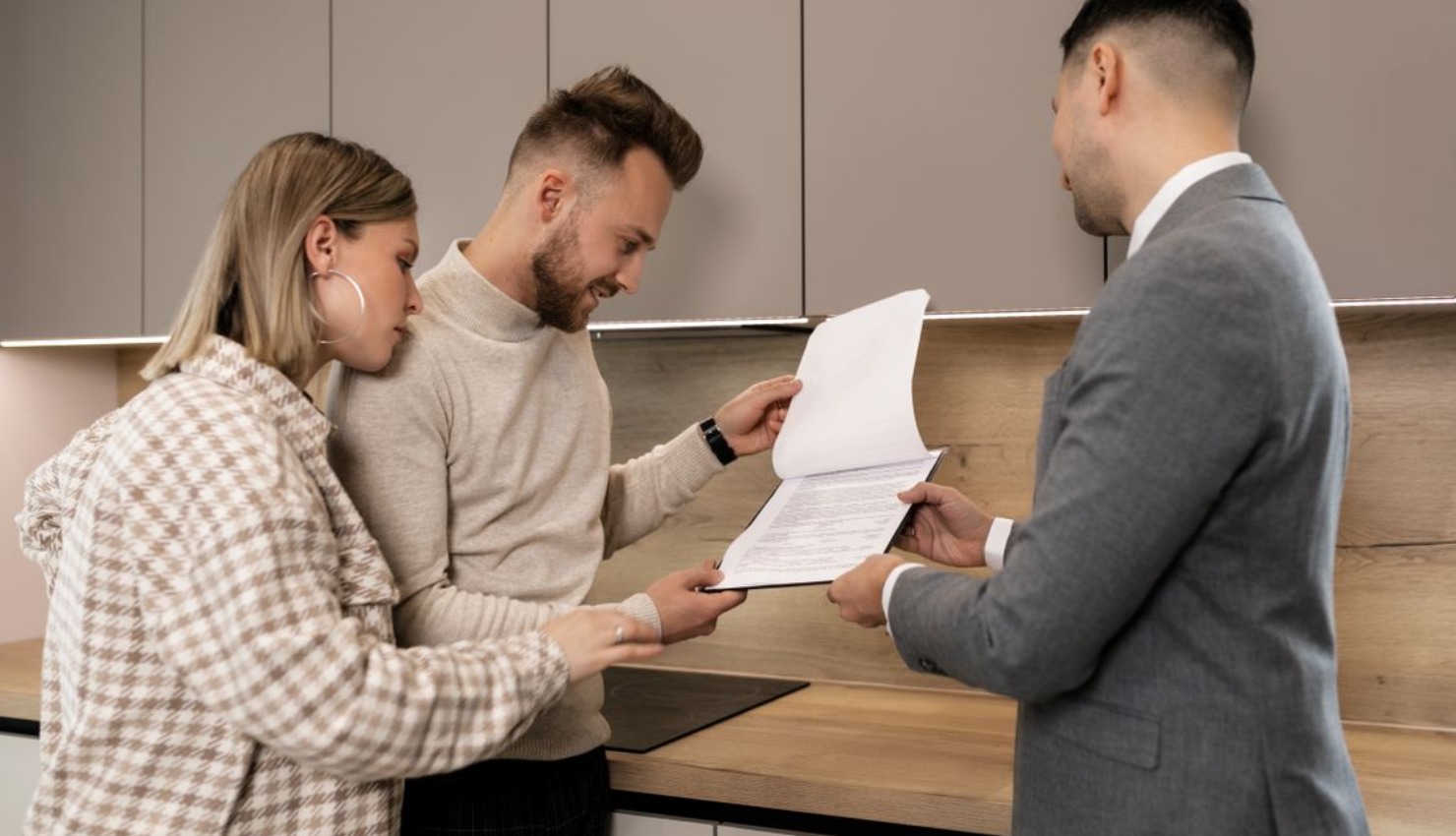 A young couple reviews contract documents presented by a residential real estate agent