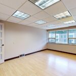Vacant modern office space with large windows and natural light, ideal for leasing.