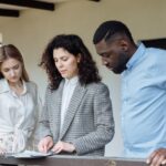 Three adults reviewing documents on a balcony during a real estate consultation